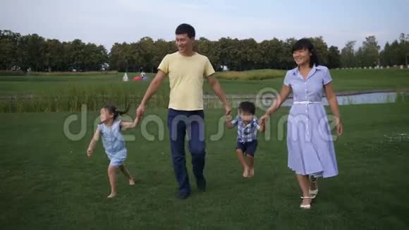 欢乐的亚洲家庭牵手漫步公园视频的预览图