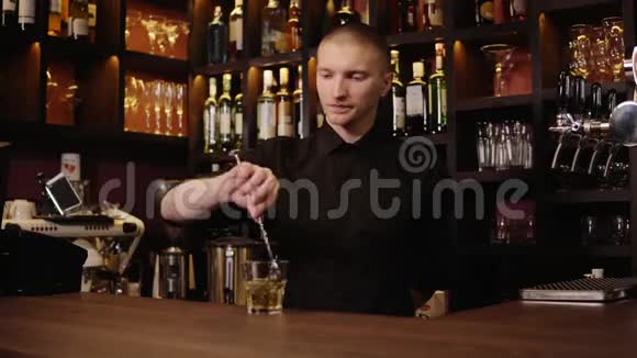 酒吧内部的年轻酒吧服务员把威士忌倒在玻璃里然后拿来给客人视频的预览图