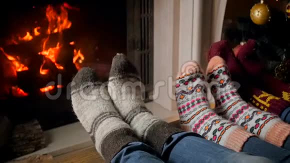圣诞前夜一家人穿着羊毛针织袜子躺在燃烧的壁炉旁缓慢移动的镜头视频的预览图