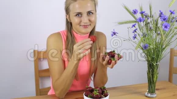 坐在厨房吃草莓的女人视频的预览图