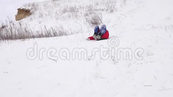 快乐的孩子在雪橇上滑雪滑梯小女孩冬天在公园里玩慢动作视频的预览图