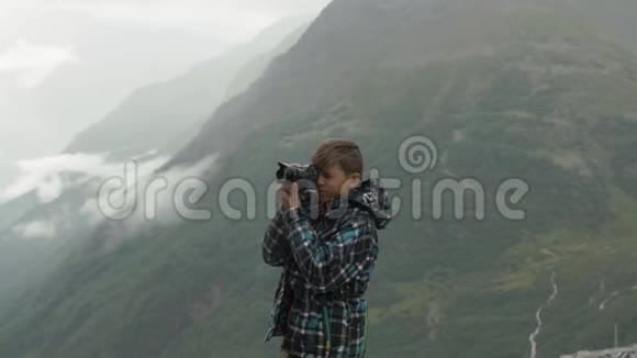 一个少年拍摄一个山景视频的预览图