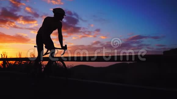 日落时分一个人骑着自行车在山路旁观看的剪影慢动作稳定视频的预览图