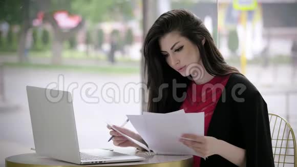 漂亮的年轻女孩穿着西装找工作填写表格或简历看着坐在咖啡馆里的笔记本电脑概念视频的预览图