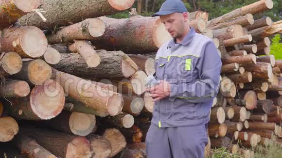 工人伐木工人或木匠在一堆木头附近有一大堆钱锯木头成功的概念视频的预览图