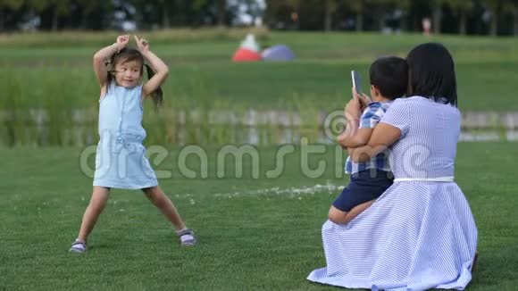 妈妈在公园给有趣的亚洲小女孩拍照视频的预览图