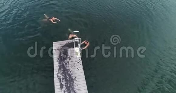 三个训练有素的人早上在室外跳入水中的无人机镜头视频的预览图