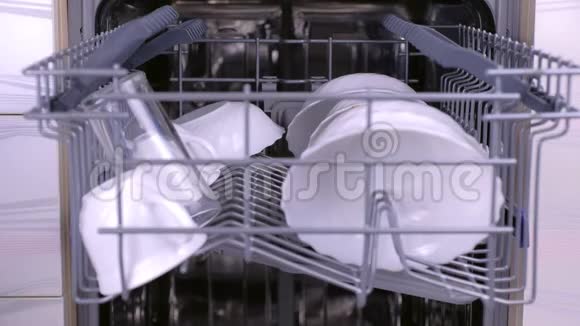男人在洗碗机里放了一个杯子把篮子然后运行洗碗机视频的预览图