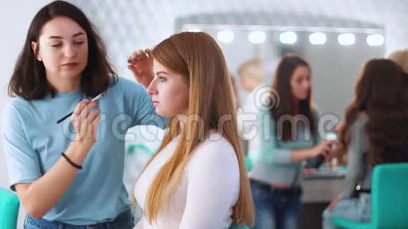 化妆师在展厅为年轻女性做专业化妆视频的预览图