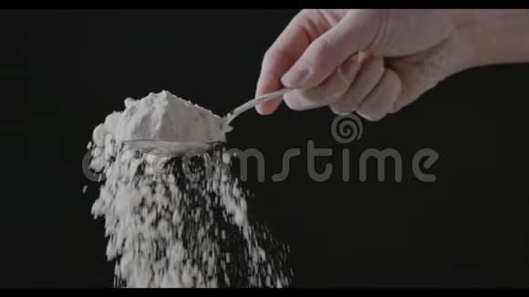 女人手拿着勺子和面粉倒在黑色的背景上慢动作全高清视频240fps1080p逐步视频的预览图
