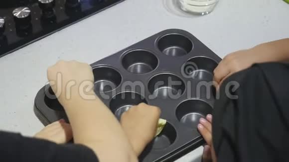 孩子们的手用黄油填充松饼模具视频的预览图