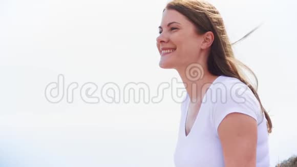年轻女子坐在蓝天上的肖像从地中海吹来的风慢慢地吹着她的头发视频的预览图