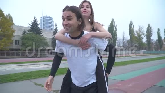 一对漂亮的年轻夫妇在户外运动帅哥在运动服上抱着一个女孩视频的预览图