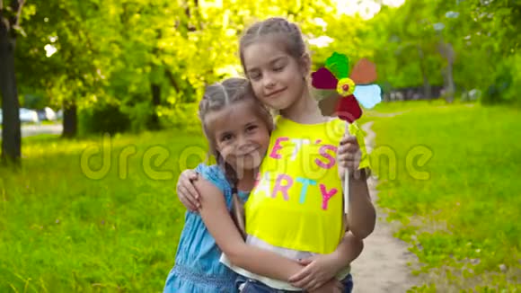 两个姐妹女孩拿着五颜六色的风车视频的预览图