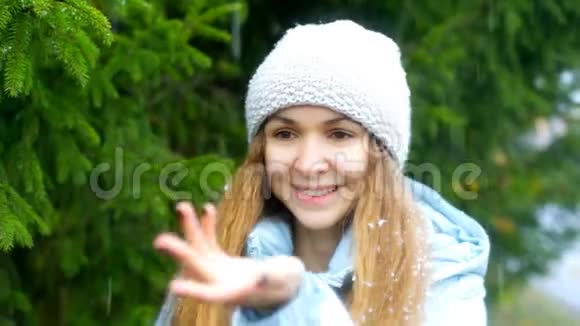 有着飘逸的头发的女孩手抓着雪花在枞树身上视频的预览图