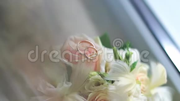 白色玫瑰上金色结婚戒指的特写视频的预览图