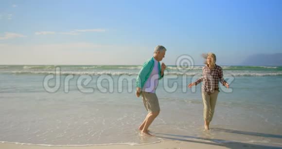 活跃的高加索族夫妇在海滩上一起跳舞的侧面景色视频的预览图