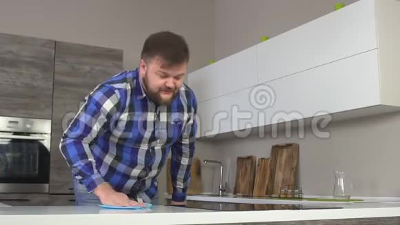穿着格子衬衫的开朗的自制男人在厨房洗了一张桌子现代的室内慢动作家务活视频的预览图