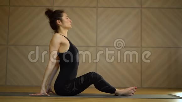 坐着做伸展运动的女孩光线极简主义工作室教室里练习瑜伽的年轻美女视频的预览图