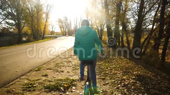 年轻女孩骑自行车在一条秋天的路上慢动作视频的预览图