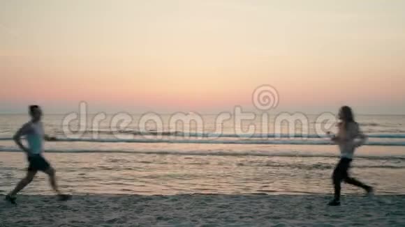 爱幸福的夫妻在夕阳下的沙滩上奔跑旋转拥抱视频的预览图