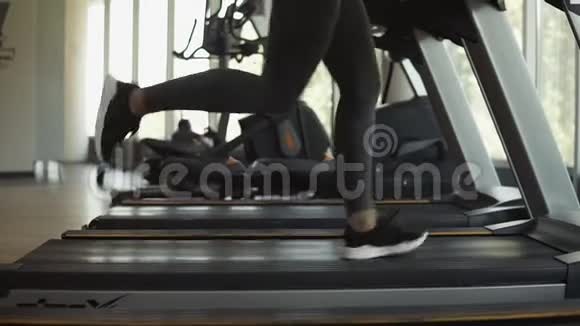 有魅力的年轻运动女性正在健身房锻炼在跑步机上做有氧训练在跑步机上跑步侧视图视频的预览图