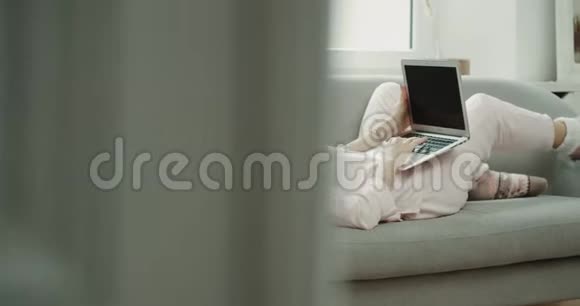 沙发上的女士穿着睡衣在笔记本上工作风格舒适视频的预览图