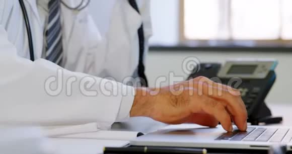 医生使用笔记本电脑同时在4k诊所的办公桌上讲座机视频的预览图