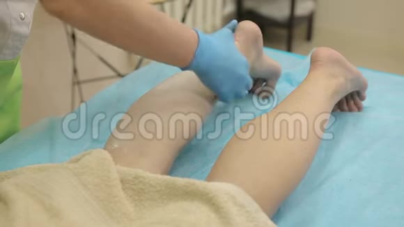水疗沙龙的脱毛蜡美容师给妇女的腿上蜡特写镜头视频的预览图