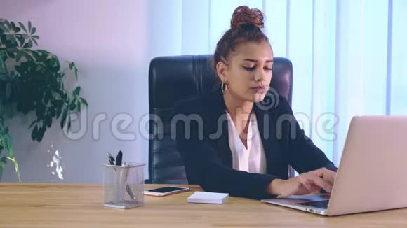 女孩穿着时髦的衣服坐在笔记本电脑附近的办公室里视频的预览图