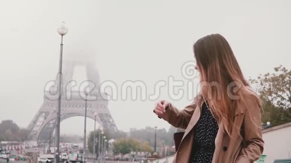 年轻时尚的女人独自站在法国巴黎的埃菲尔铁塔上清晨雾蒙蒙的慢动作视频的预览图