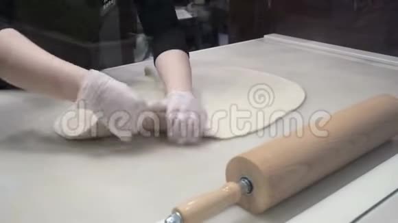 场景库克在手的帮助下对齐桌上的面团塑造面团肉桂卷的生产视频的预览图