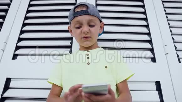 小男孩玩游戏时使用手机的特写穿T恤的漂亮男孩的画像很聪明视频的预览图