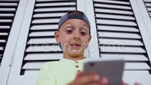 有趣可爱的小男孩在智能手机上玩游戏5岁6岁的小男孩手里的电话离他的脸太近了视频的预览图