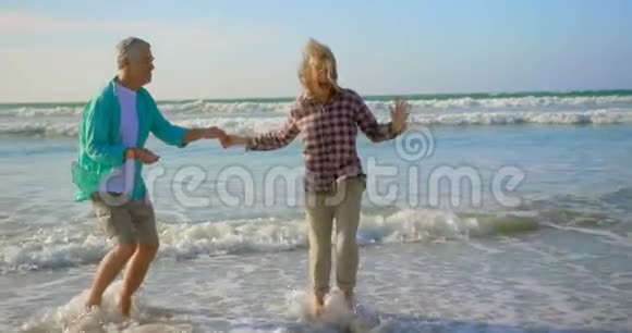 活跃的高加索族夫妇在海滩上一起跳舞的侧面景色视频的预览图