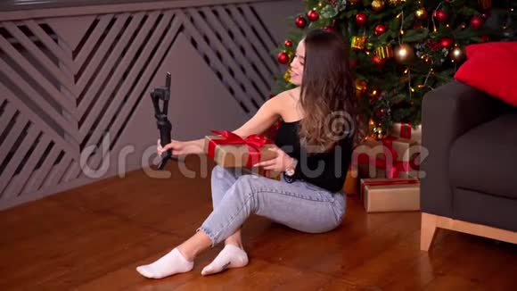 年轻女性博客作者正在用一个稳定器在电话上广播圣诞节和新年一边挤视频的预览图