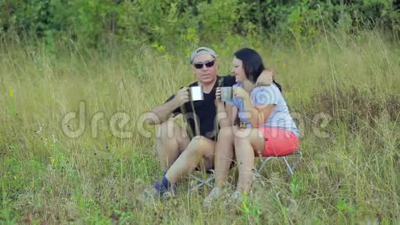 幸福的一对夫妻坐在森林的边缘喝着杯子里的茶视频的预览图