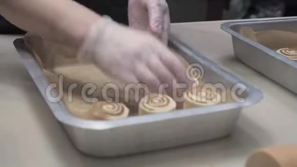 场景库克把准备好的面包和肉桂放在金属烤盘上生产肉桂卷面包制品视频的预览图