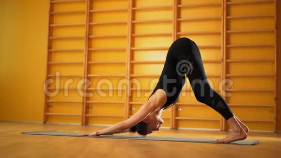 女人在室内的黄色教室里做伸展腿黑人青年女子练瑜伽光极简主义视频的预览图
