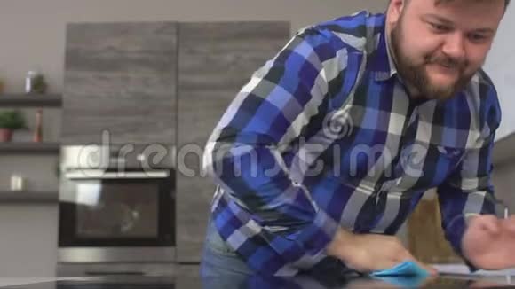 留着胡子的长胡子胖子在家里的现代化厨房里洗了一张桌子动作缓慢视频的预览图