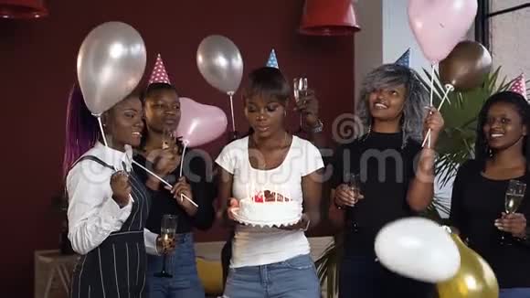 快乐迷人的非洲女孩在生日蛋糕上吹蜡烛包围了她的朋友视频的预览图