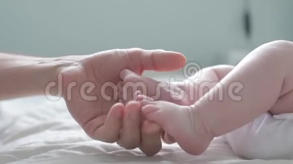 父亲抚摸并数着他的新生儿小脚趾关上门父母抱着新生儿的脚快乐的父母视频的预览图