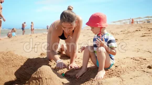 小蹒跚学步的男孩和他的母亲在EA海滩玩的4k视频在暑假玩玩具和放松视频的预览图