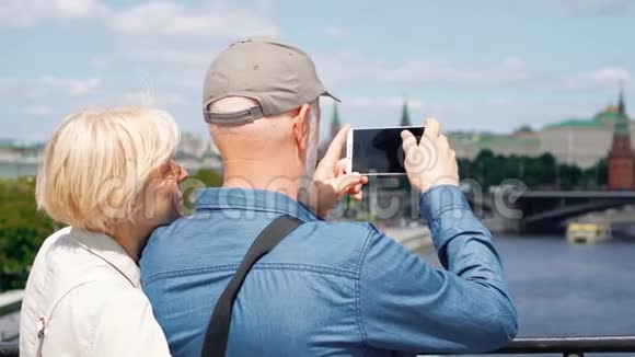 高层情侣站在观景台上用手机拍摄城市的旅游照片视频的预览图