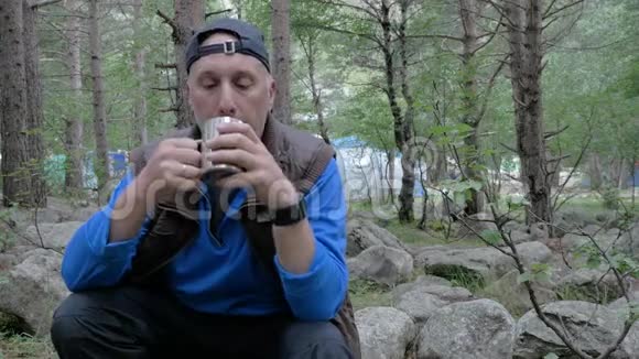 一个留着灰色胡须的白人在森林里旅行他休息喝茶视频的预览图