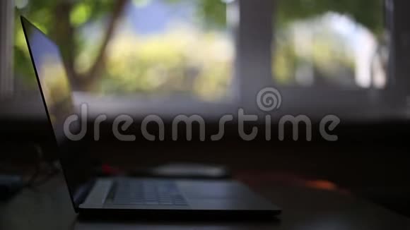 家用木制桌子上的现代笔记本电脑带有bokeh的窗口背景视频的预览图