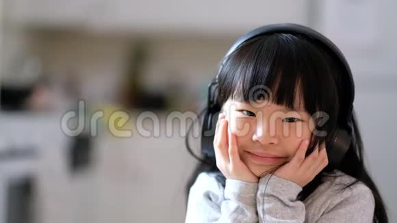 一个年轻的亚洲女孩喜欢听耳机上的音乐视频的预览图