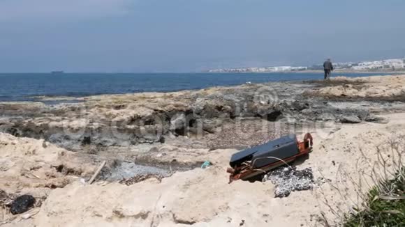岩石海滩上的金属垃圾背景是渔夫和船海洋污染视频的预览图