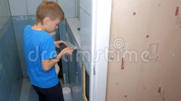 小男孩在家做翻新修理他从厕所的墙上移除瓷砖视频的预览图