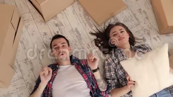 一对幸福的夫妇躺在新公寓的地板上把枕头扔掉视频的预览图
